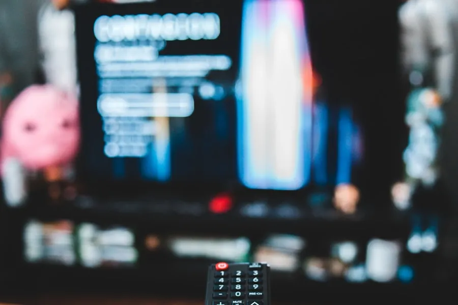 Hand holding a remote in front of a TV, loading an IPTV playlist
